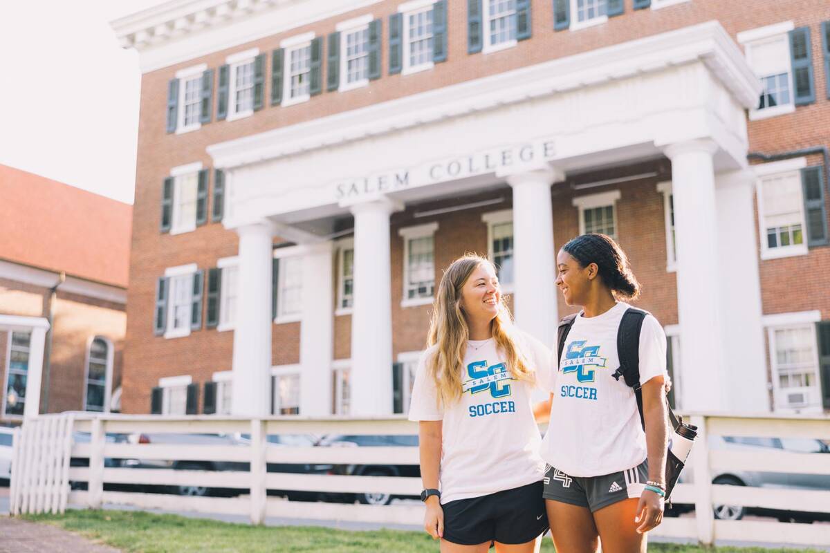 Two Salem College Students in Soccer shirts in front of Salem Building